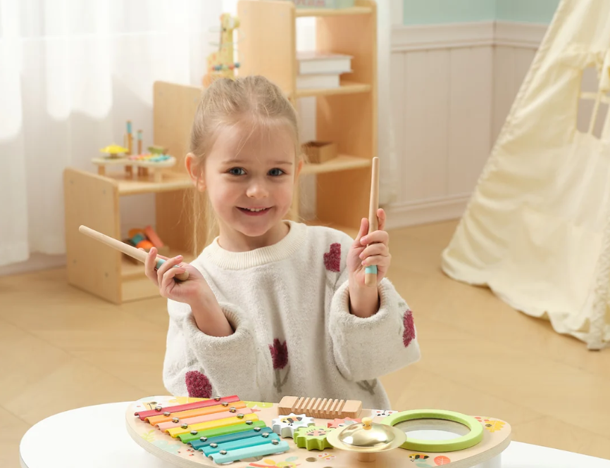 A child playing happily with a colourful wooden instrument table